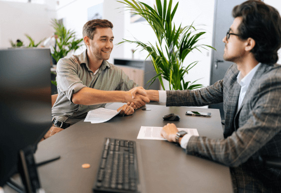 Two businessmen shaking hands across a desk